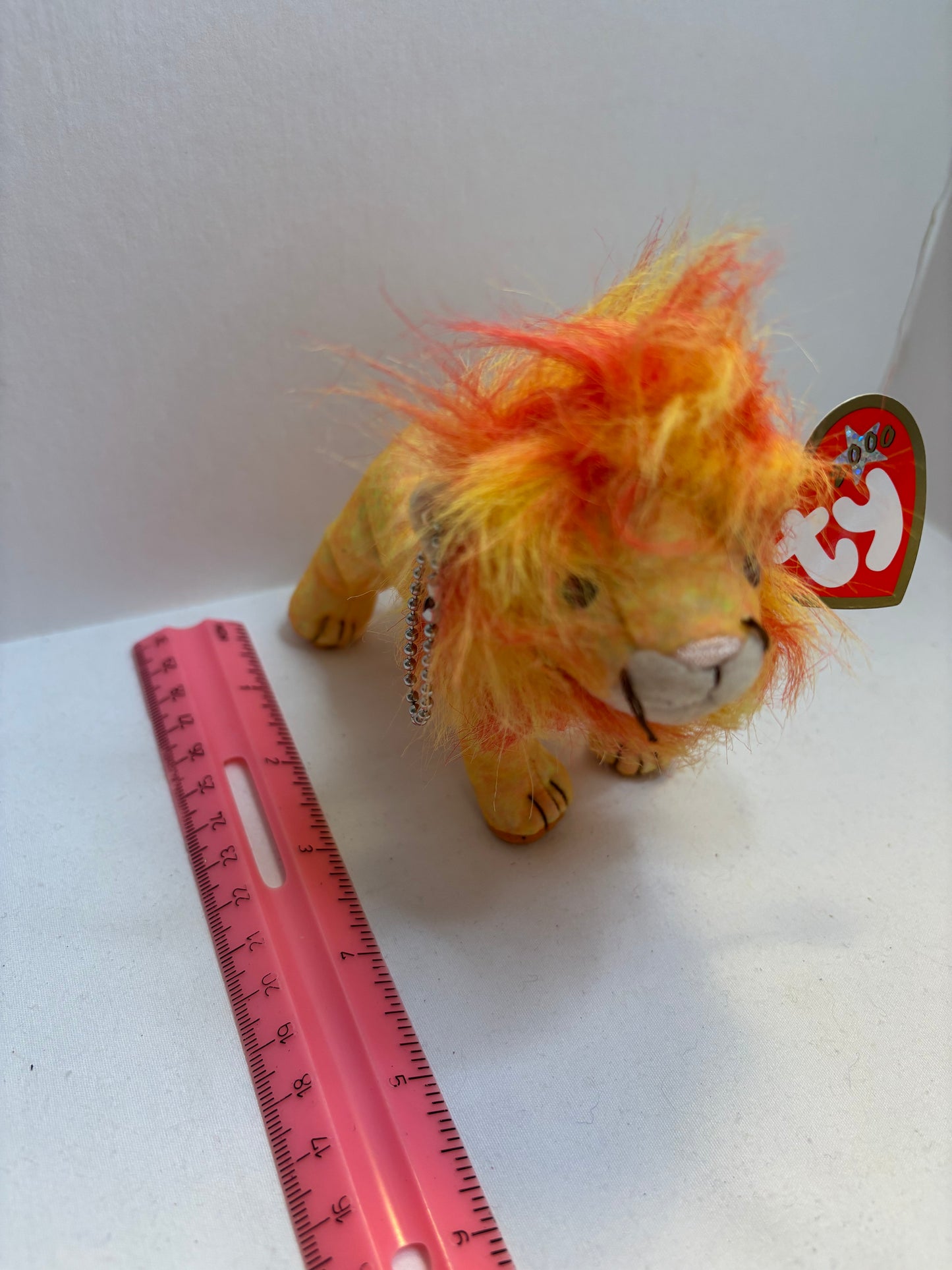 Plush orange lion bag charm with a Beanie Baby tag on a white background