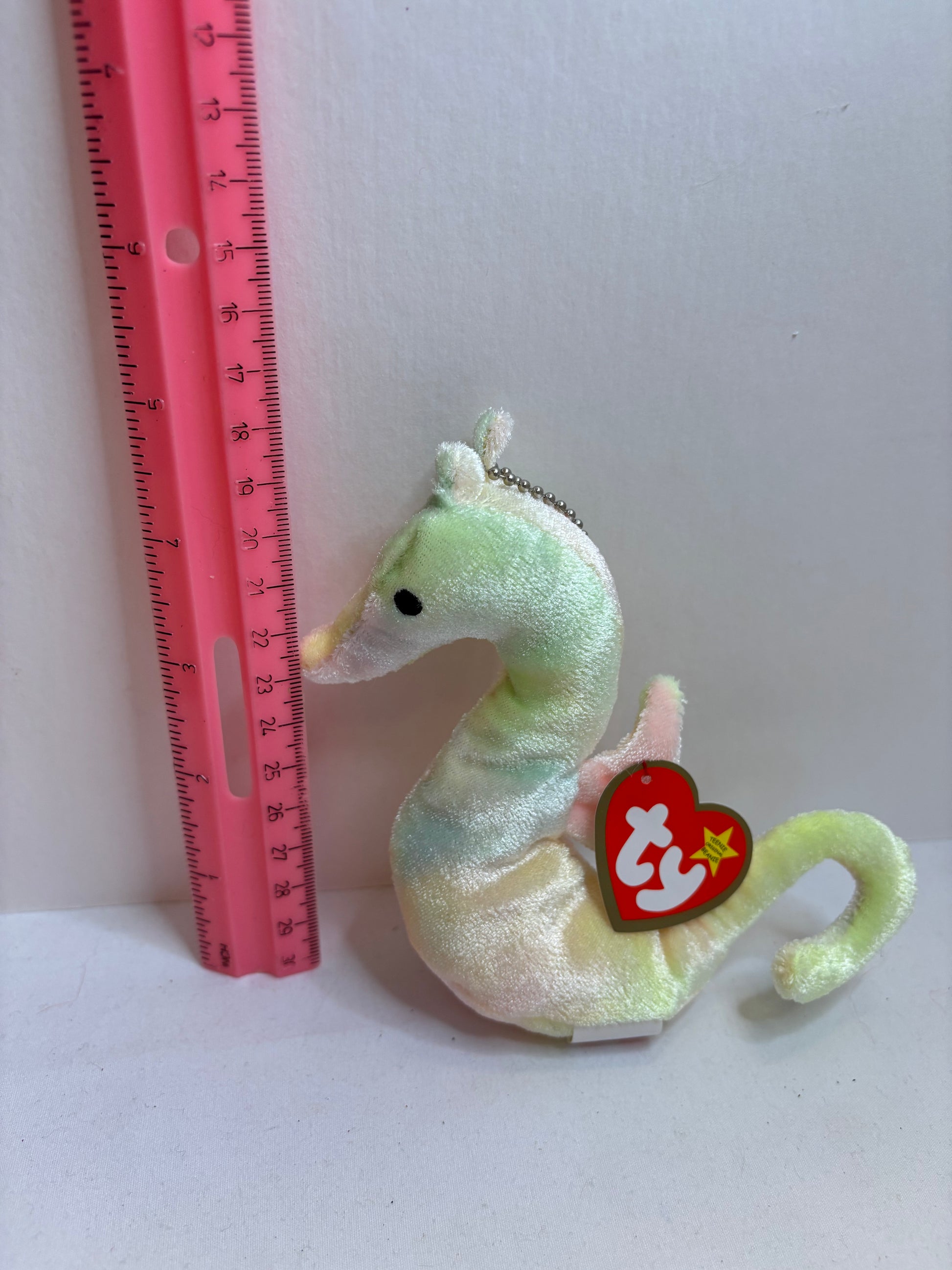 Pastel Plush seahorse bag charm with a red tag on a white background