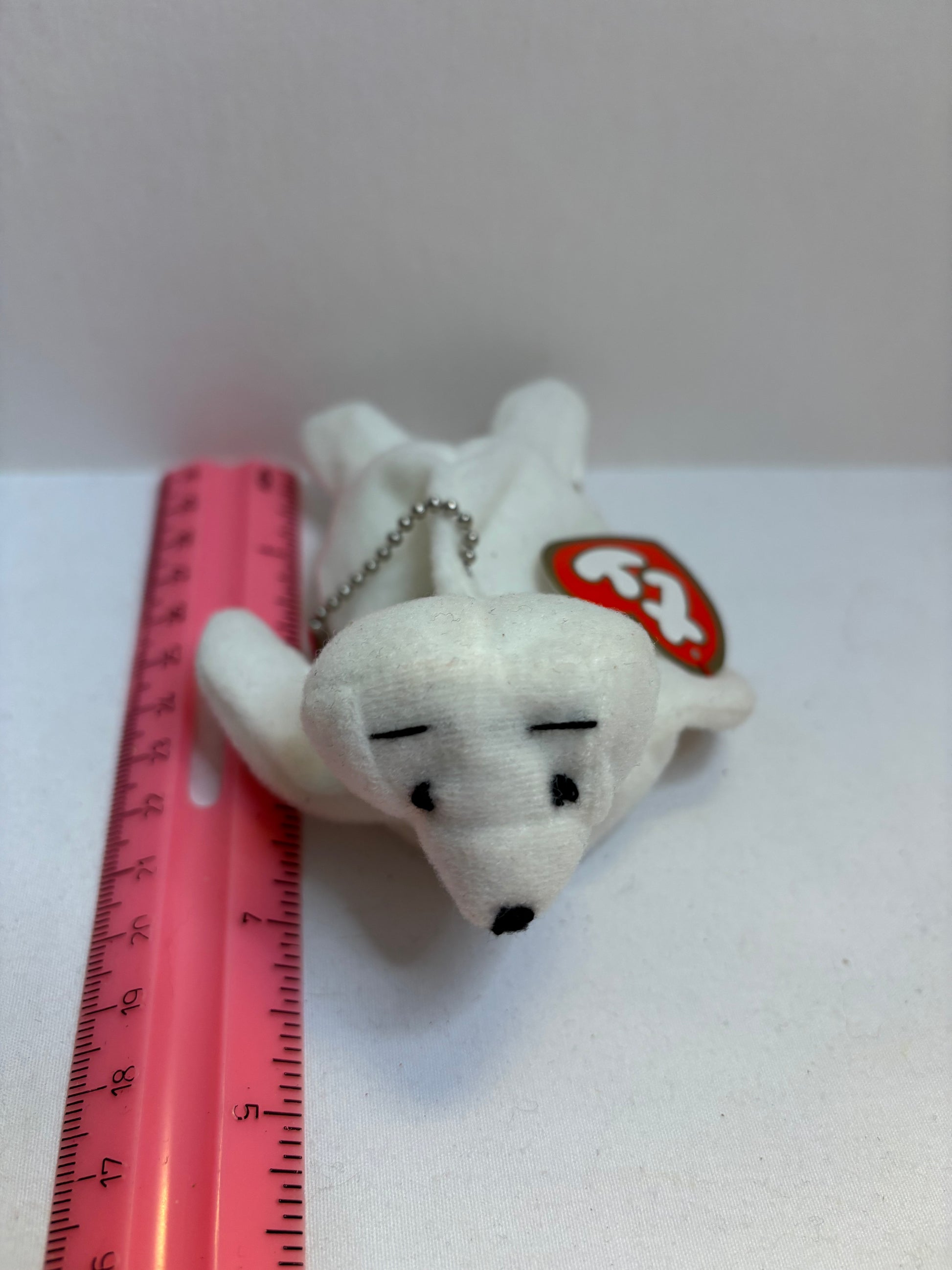 White plush seal bag charm with a red and white tag on a white background