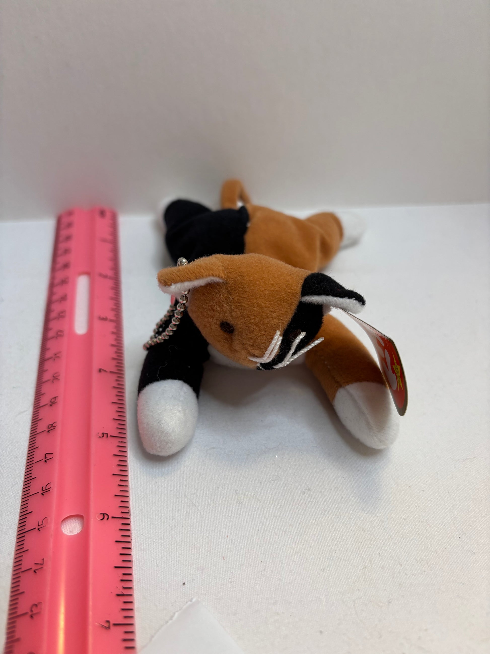 Plush brown black and white cat bag charm on a white surface