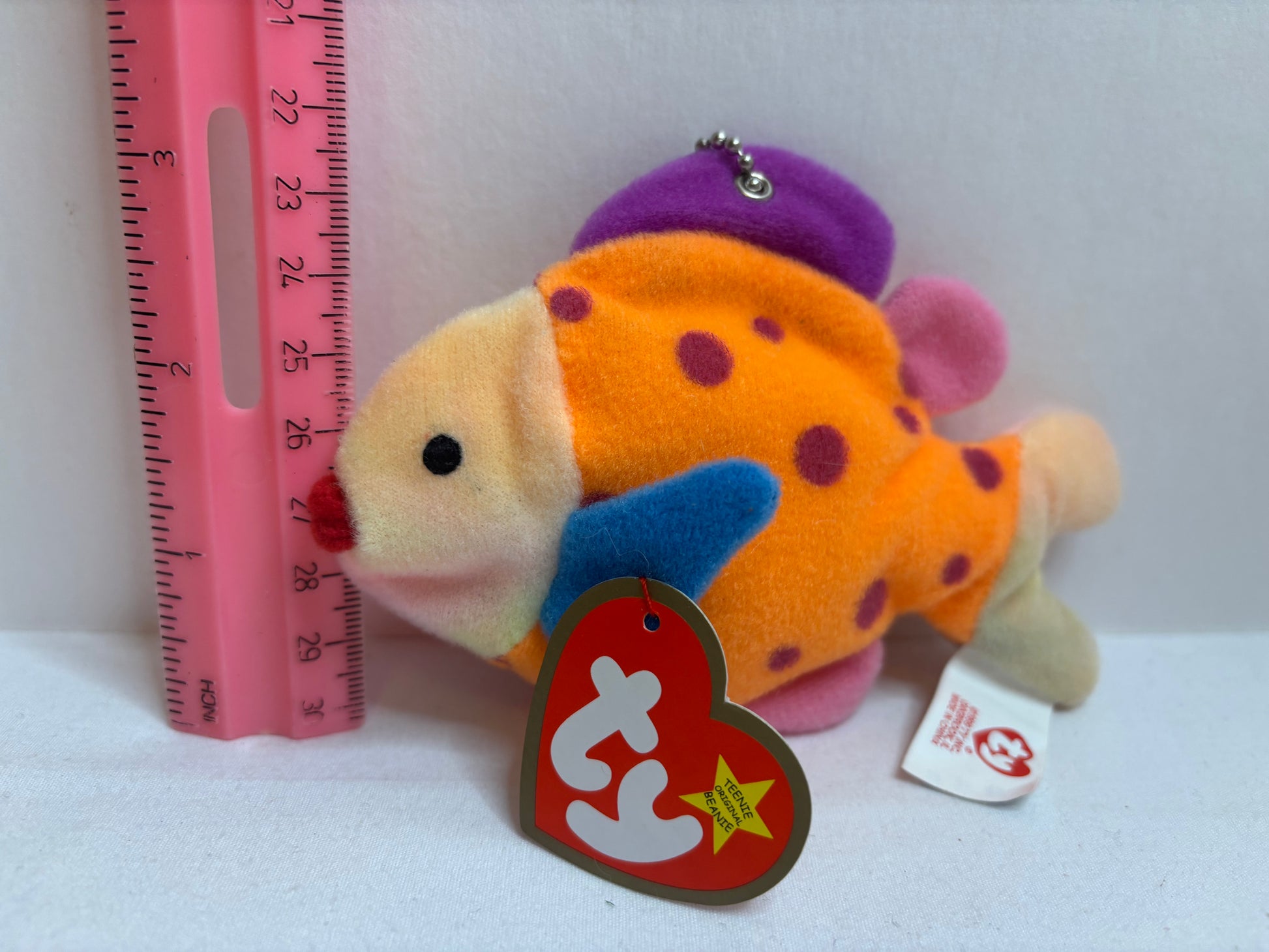 pink orange and purple Plush fish bag charm with red polka dots on a white background