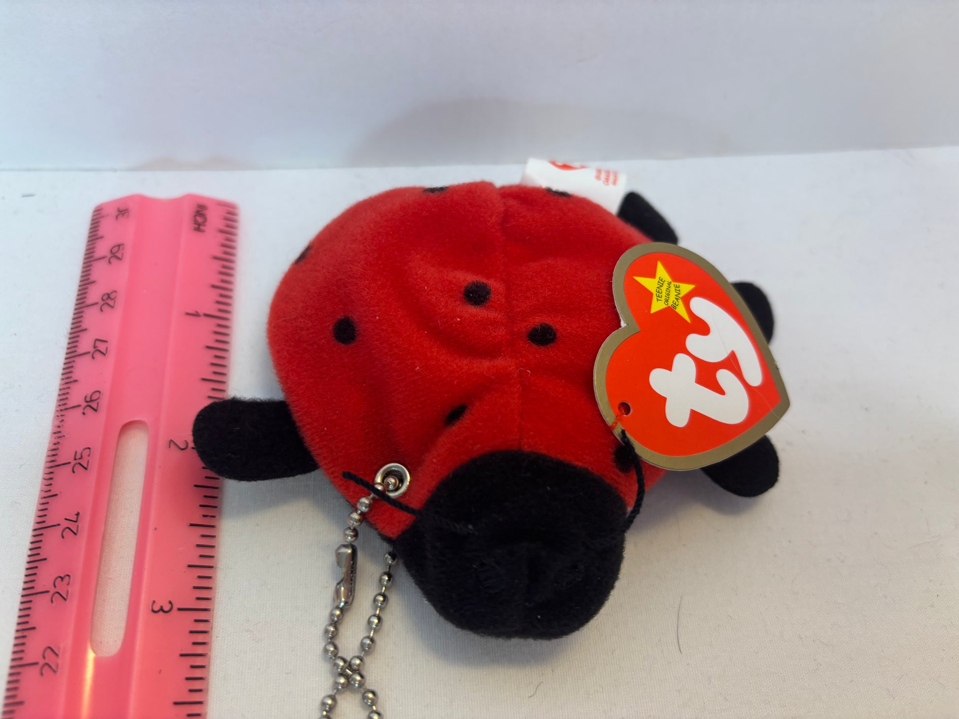 Plush red ladybug bag charm on a white background