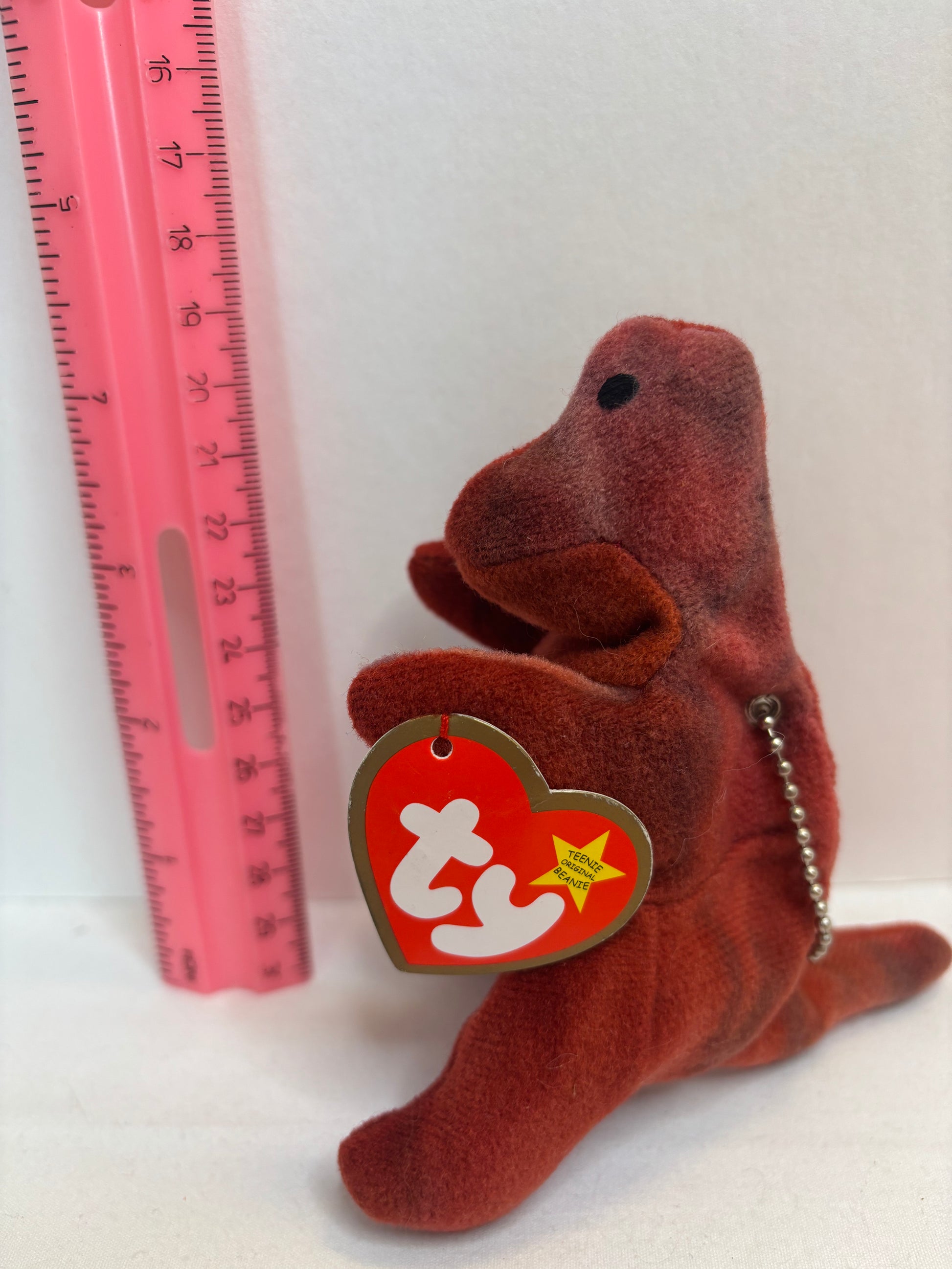 dark Red plush t rex bag charm with a tag on a white background